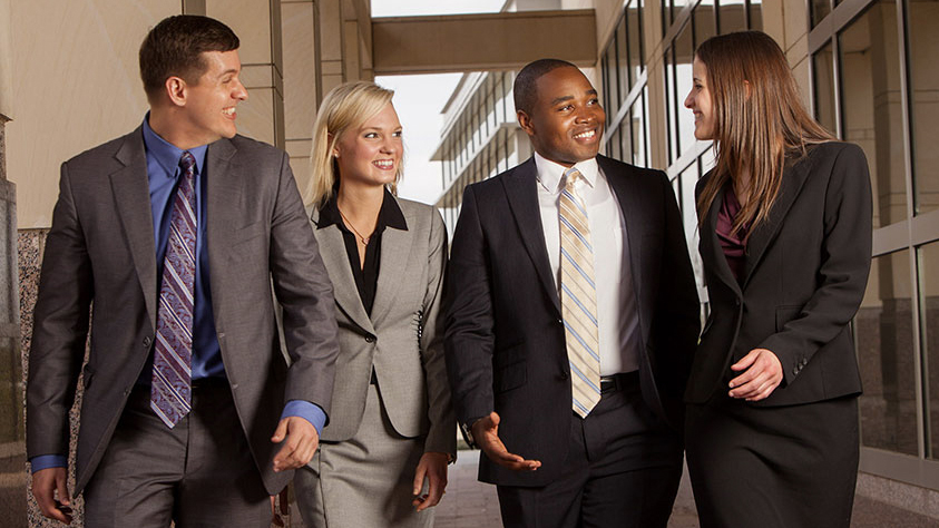 Bush School of Government and Public Service students, dressed in professional attire, walk together after class