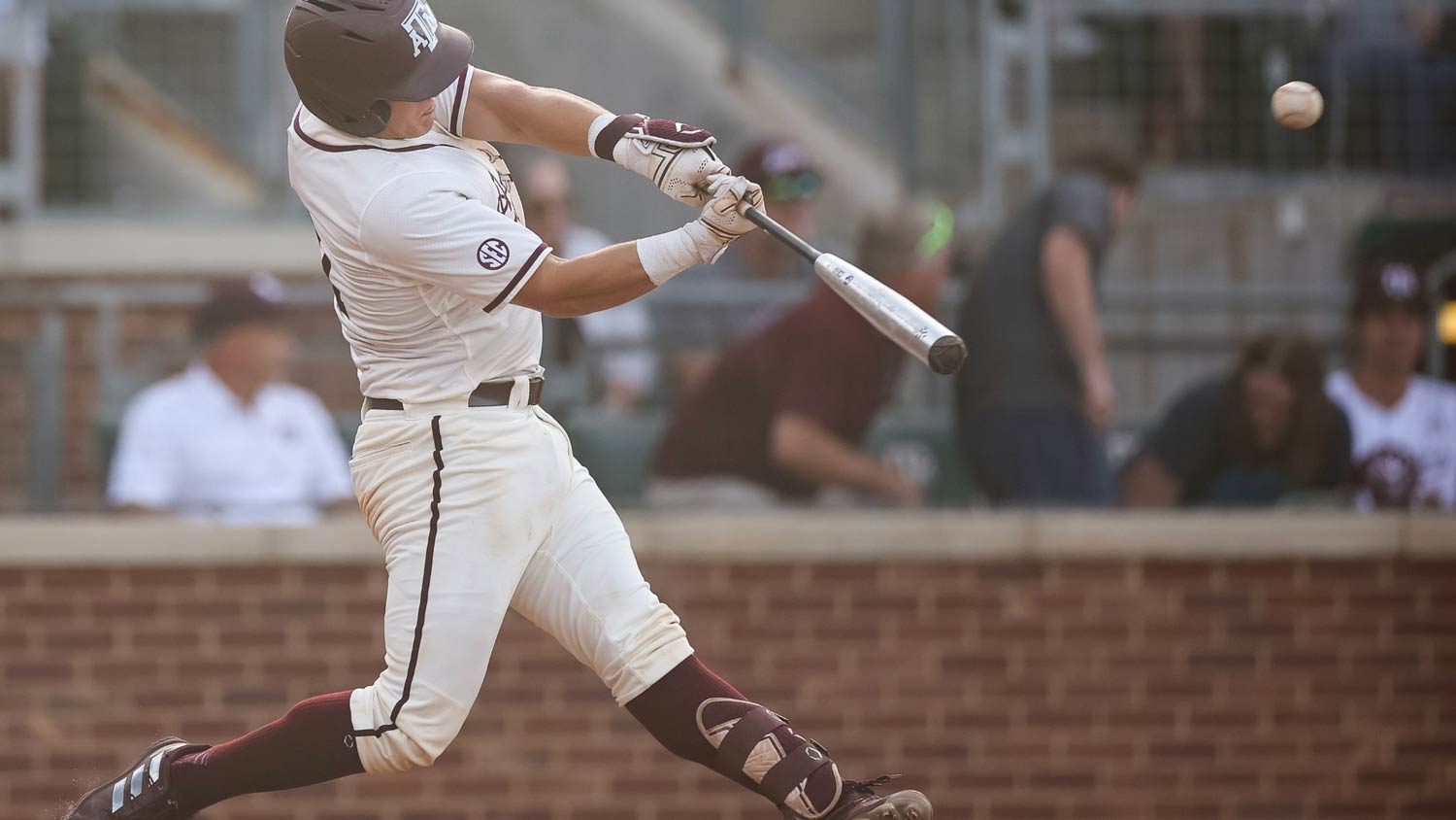 A Texas A&M baseball player at bat hits the ball