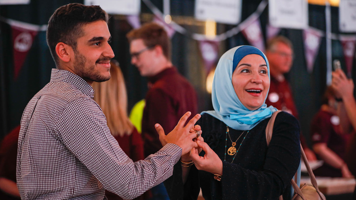 A mother puts on her sons' Aggie ring for the first time at Ring Day