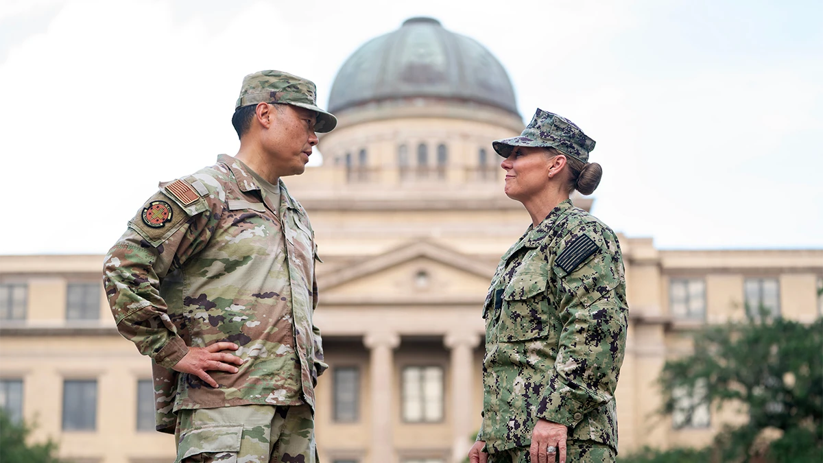 Two veterans in military fatigues talk outside of the Texas A&M Academic Building