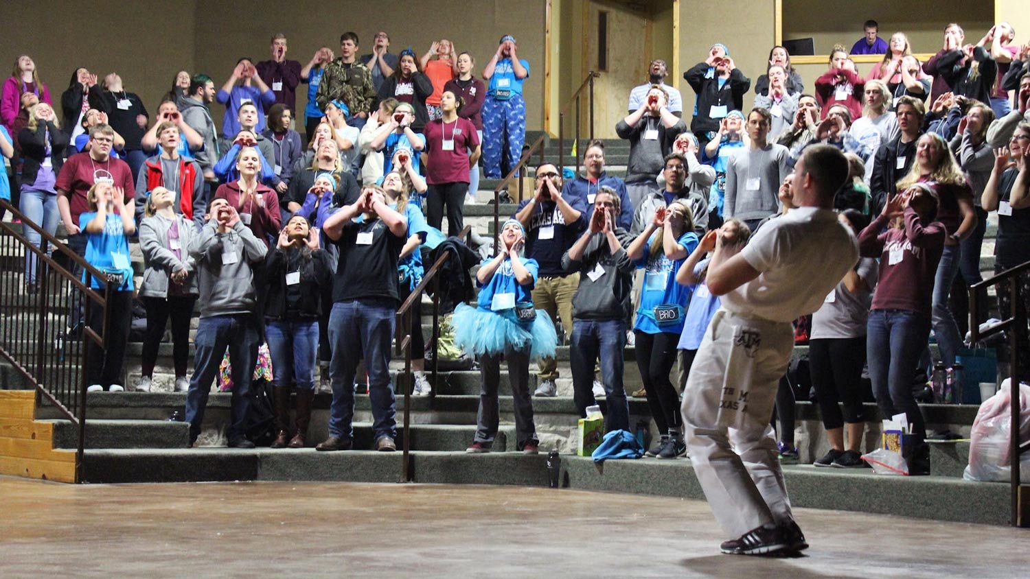 A group of new freshman practice yells with a yell leader