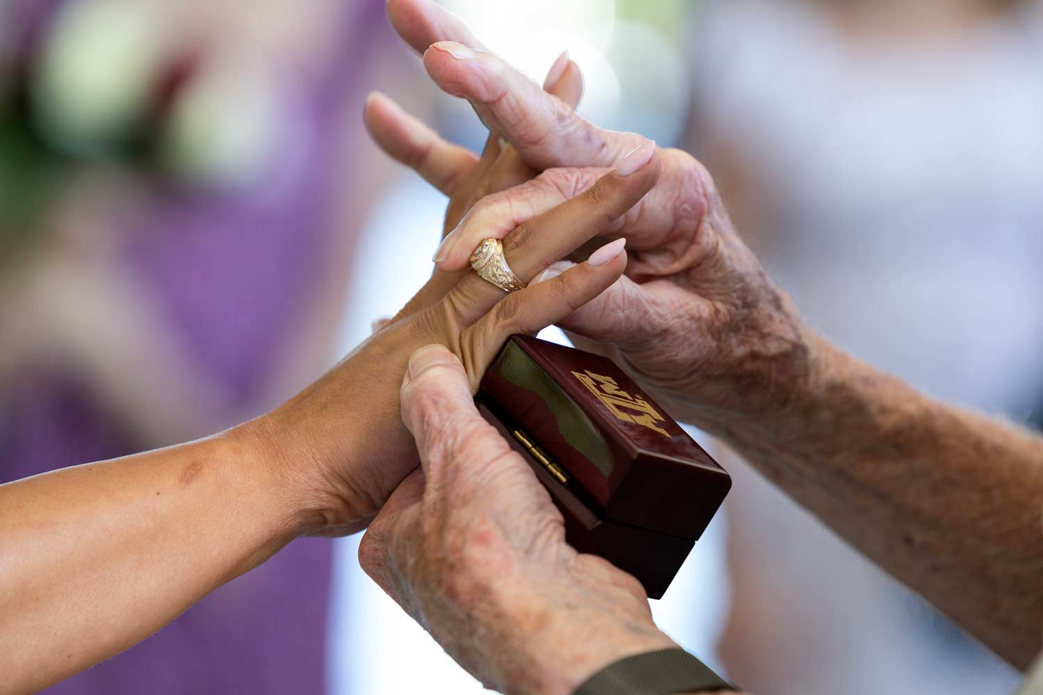 Older relative puts on the Aggie ring of a TAMU student for the first time at her ring day ceremony