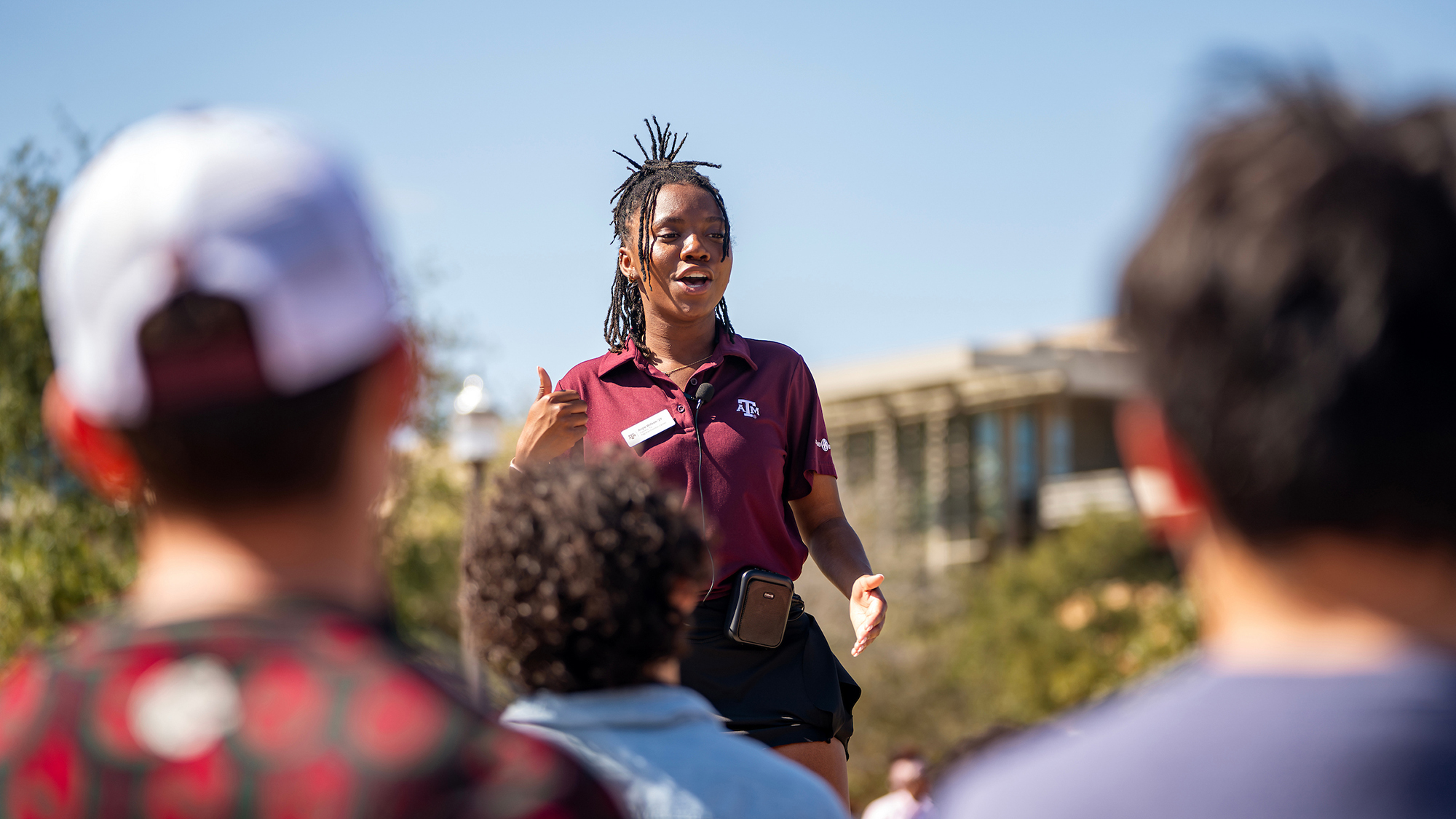 A university tour guide engages with prospective students during an outdoor campus tour.